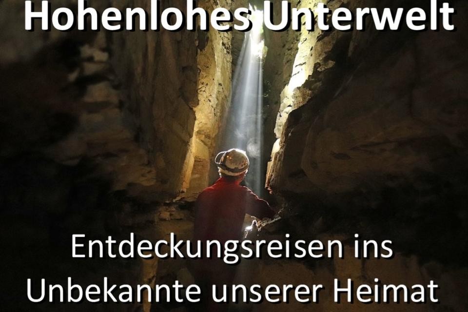 Ein Plakat, auf dem ein Mensch mit Helm durch eine Höhle wandert. Der Titel der Veranstaltung steht auf dem Plakat