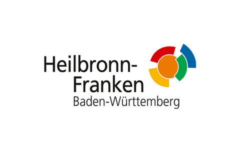 Logo der Wirtschaftsregion Heilbronn- Franken Baden-Württemberg. Schwarze Schrift auf weißem Hintergrund: Wirtschaftsregion Heilbronn-Franken Baden-Württemberg. Gelb, rot, orange, grün, blauer Kreis rechts oben.